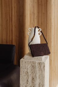 Kaboompics - Woven Handbag on a Travertine Pedestal with White Vase