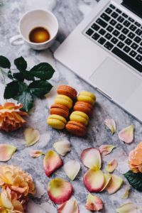 Kaboompics - Coffee and Macarons beside a Laptop on Marble with Peach Rose Petals