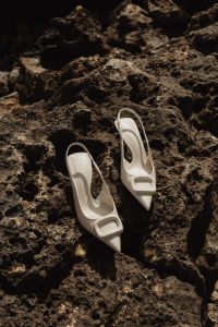 Kaboompics - White Buckle Mules on Dark Textured Rocks