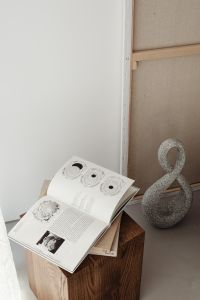 Kaboompics - Open Book and Stone Sculpture on Wooden Pedestal with Copy Space