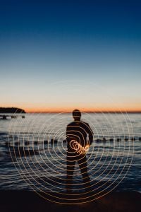 Kaboompics - Light painting. The man waving fairy lights at the sea at sunset.