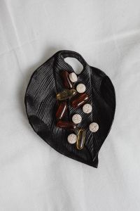 Kaboompics - Mixed Vitamins and Tablets on a Black Leaf with Copy Space