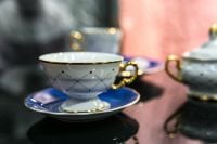 Kaboompics - Close-Up of Blue-Patterned Porcelain Teacup with Gold Rim on a Reflective Table