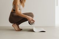 Kaboompics - Crouching Woman Unrolling a Yoga Mat on the Floor