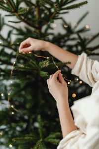 Kaboompics - Hands Hanging Warm Lights on Christmas Tree