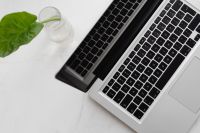 Kaboompics - Overhead Laptop, Calendar and Green Leaf in Glass on White Marble, Work From Home Flat Lay