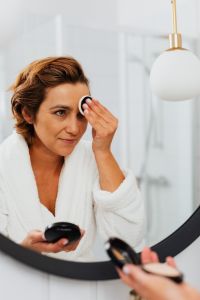 Kaboompics - Vertical Portrait of a Woman Applying Pressed Powder with a Makeup Sponge at a Bathroom Mirror