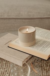 Kaboompics - Beige Candle on Open Book with Gray Sofa Background