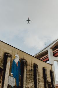 Kaboompics - Airplane Passing above an Eagle-Headed Suit Mural at LX Factory, Lisbon, Portugal