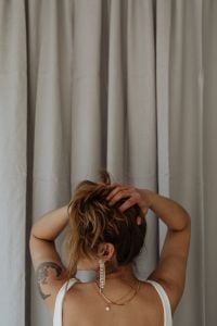 Kaboompics - Woman Adjusting Her Hair in a White Tank Top and Long Earrings