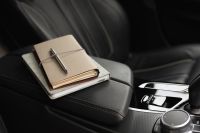 Kaboompics - Stacked Notebooks and Pen on a Black Car Armrest