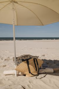 Kaboompics - Beach Umbrella, Straw Bag and Folded Towel by the Sea