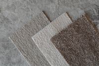 Kaboompics - Three Neutral Bouclé Upholstery Fabric Swatches on Gray Stone