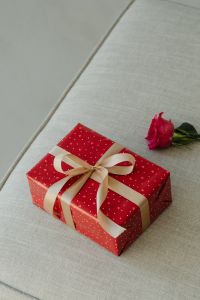 Kaboompics - Red Heart Print Gift Box and Pink Rose on Beige Upholstery