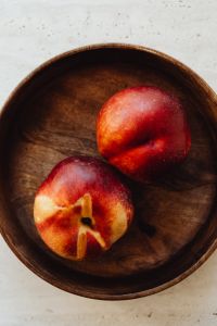 Kaboompics - Close-Up of Two Peaches in Wooden Bowl on Light Stone Background