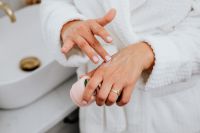 Kaboompics - Woman Applying Hand Cream beside a Bathroom Sink, White Robe Beauty Routine