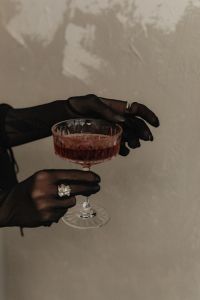 Kaboompics - Black Gloved Hands Around a Red Cocktail Glass