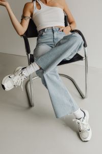 Kaboompics - Seated Woman Crossing Legs in Light Blue Jeans and White Sneakers, Casual Studio Fashion