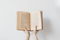 Kaboompics - A young woman in a woolly sweater holds books