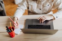 Kaboompics - Woman Typing on Laptop Beside Notebook