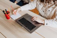 Kaboompics - Woman Using Laptop Beside Open Notebook