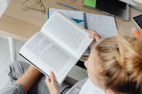 Kaboompics - Student Reading Textbook with Notebook and Laptop