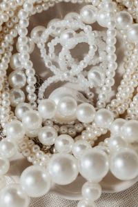 Kaboompics - Large Pearl Strand and Layered Necklaces in a Scalloped Dish, Vertical Neutral Flat Lay