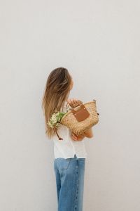Kaboompics - Woman Carrying Woven Tote with Daisies and Minimal Copy Space