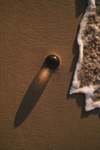 Kaboompics - Black Glass Sphere Beside Foamy Shoreline