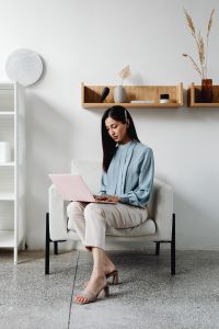 Kaboompics - Asian Woman Working on a Pink Laptop in a Minimalist Living Room