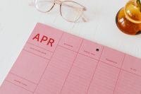 Kaboompics - Close-Up Pink Weekly Planner Checklist with Glasses and Amber Vase for Productivity Mockups