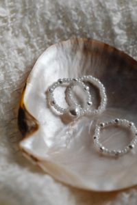 Kaboompics - Pearl Bead Rings Arranged Inside an Iridescent Seashell, Vertical Flat Lay