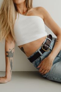 Kaboompics - Woman’s White Ribbed Crop Top, Gold Chain and High-Waisted Denim, Minimal Studio Fashion