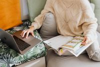 Kaboompics - The woman is reading the newspaper and using a laptop