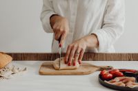 Kaboompics - Woman Slicing Rustic Bread on a Wooden Board
