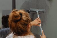 Kaboompics - Woman Cleaning a Glass Window Beside Indoor Cactus