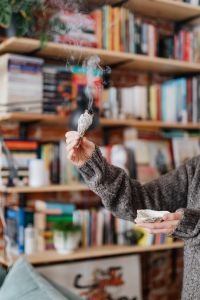 Kaboompics - Hand Holding Smoking Sage in a Home Library, Spiritual Cleansing Ritual