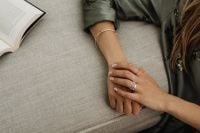 Kaboompics - Silver Rings and Hands Resting Together Beside an Open Book on the Sofa
