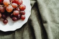 Kaboompics - Red Grapes on a White Plate against Olive Linen Texture