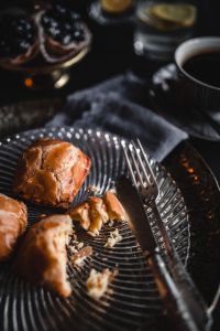 Kaboompics - Golden Sweet Buns and Silver Cutlery on a Dark Plate