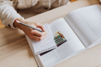 Kaboompics - Woman Writing in Notebook Beside Open Book