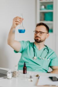 Kaboompics - Doctor Presenting Blue Flask Against Office Background
