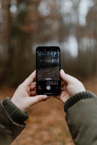 Kaboompics - A woman takes a picture with her iPhone X in the autumn forest
