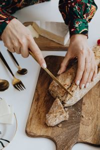 Kaboompics - Close-Up of Hands Slicing Rustic Bread