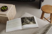 Kaboompics - Open Art Book on Beige Sofa with Travertine Coffee Table
