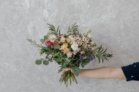 Kaboompics - Large Mixed Flower Bouquet Held by an Arm against a Pale Textured Studio Wall