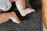 Kaboompics - Newborn Baby's Bare Feet on Dark Rug Beside Wooden Floor