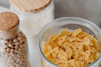 Kaboompics - Glass Chickpea Jar beside a Bowl of Farfalle Pasta on a White Counter