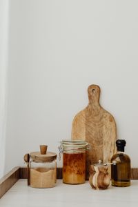 Kaboompics - Pantry Ingredient Jars, Wooden Cutting Boards and Olive Oil on a Neutral Kitchen Counter