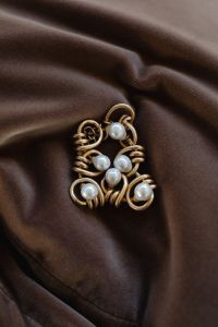 Kaboompics - Gold Wire and Pearl Jewelry Detail on Draped Brown Satin, Elegant Fashion Still Life